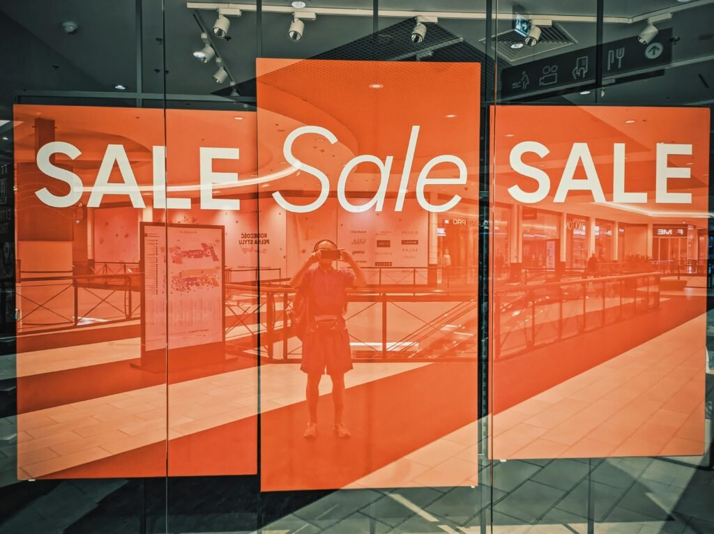 Ein Einzelhandels-Schaufenster mit großem Sale-Schild, das auf eine Rabattaktion hinweist, fotografiert bei Tag