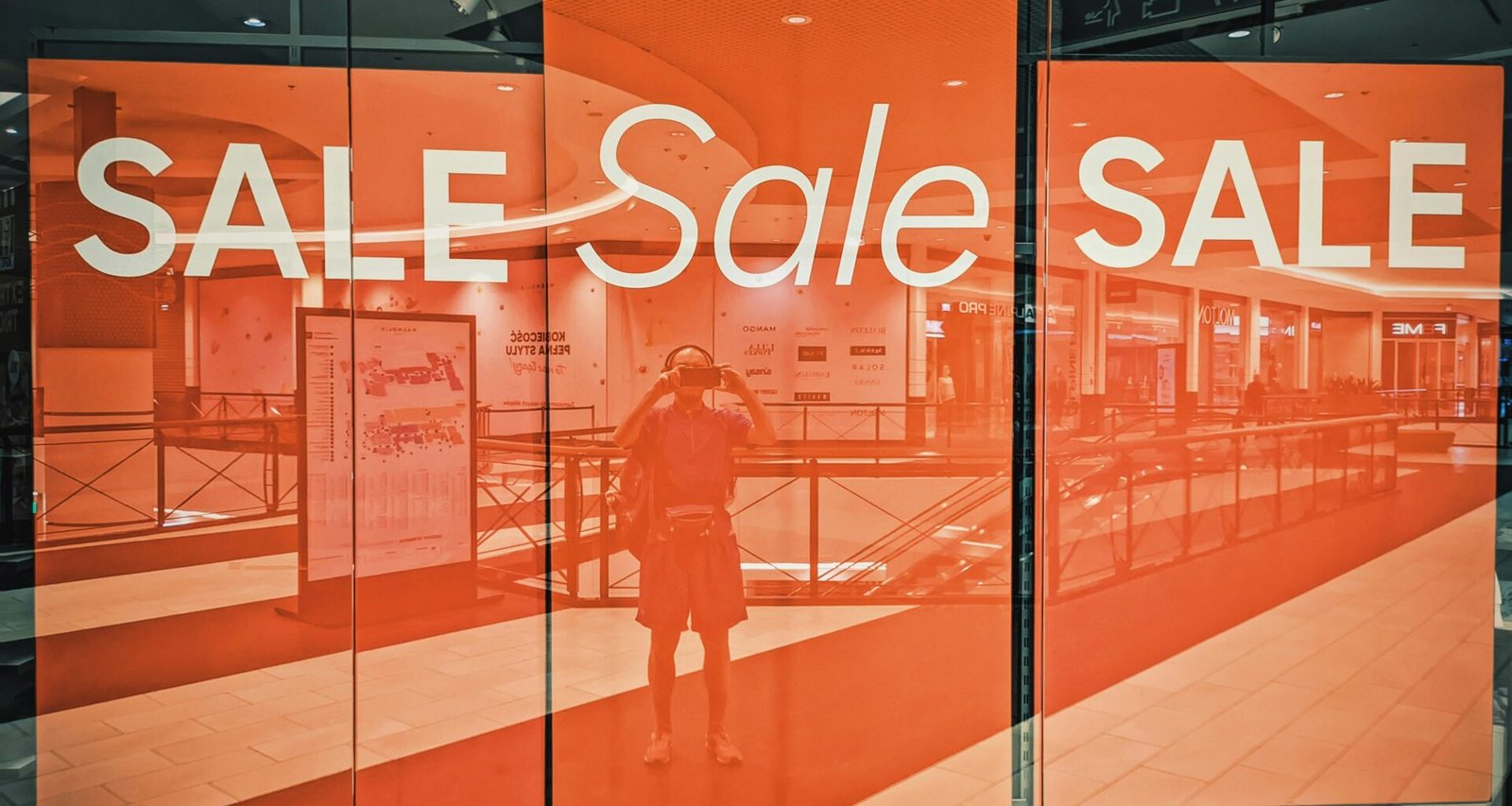 Schaufenster eines Geschäfts mit auffälligem Sale-Schild und reflektierender Glasfront in einer Einkaufsstraße