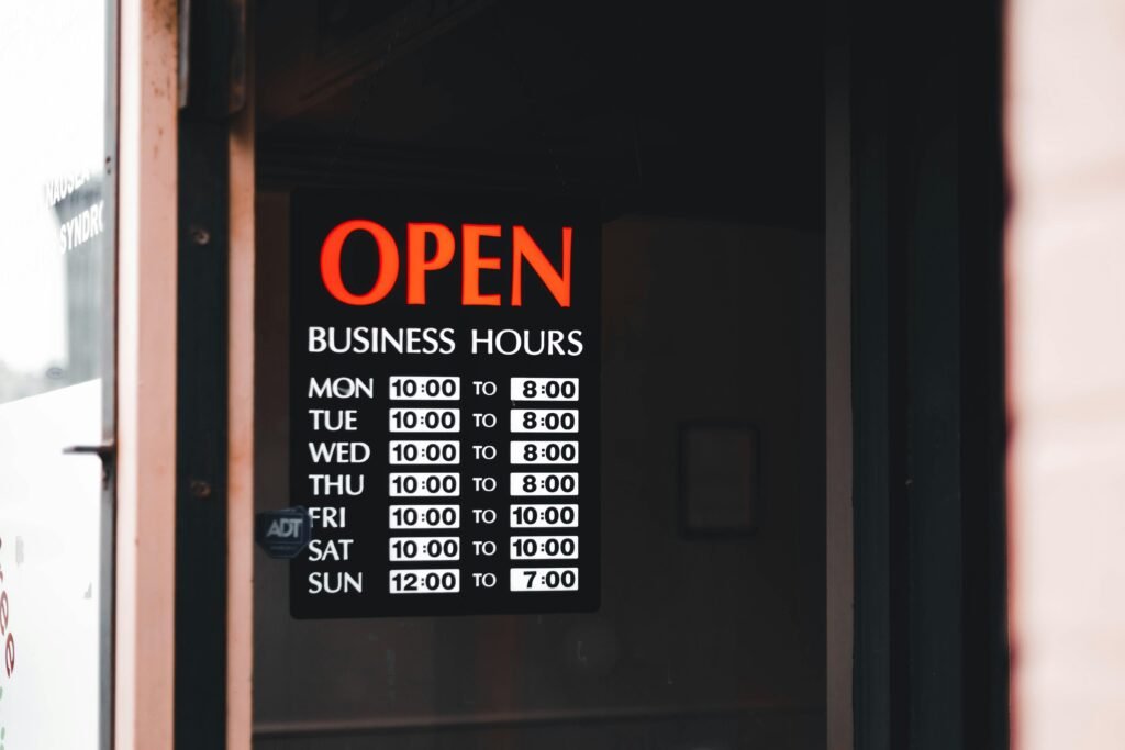 Tür mit einem Schild, das auf die aktuellen Öffnungszeiten eines Geschäfts hinweist, englischer Text: Open Business Hours