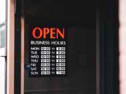 Tür mit einem Schild, das auf die aktuellen Öffnungszeiten eines Geschäfts hinweist, englischer Text: Open Business Hours