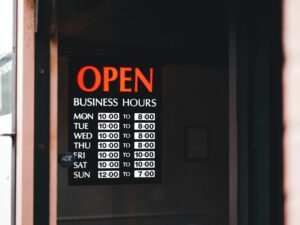 Tür mit einem Schild, das auf die aktuellen Öffnungszeiten eines Geschäfts hinweist, englischer Text: Open Business Hours