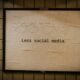 Schild an einer Wand mit dem Schriftzug 'less social media' als Hinweis für bewusste Social-Media-Nutzung