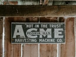 Ein rechteckiges Schild ist an einer Hauswand in einer modernen Stadt befestigt und steht im Blickpunkt der Fotografie.