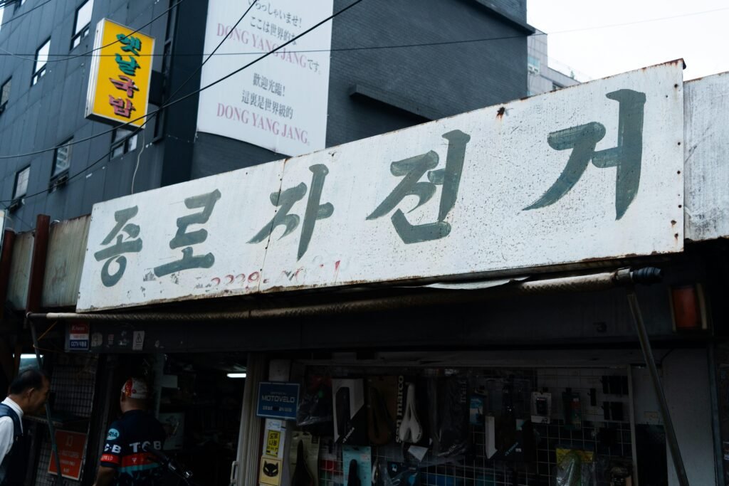 Ein Schild mit koreanischem Text hängt über dem Eingang eines Geschäfts und hebt die typische Beschilderung koreanischer Läden hervor.