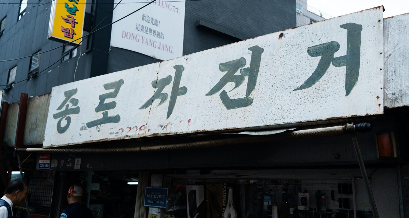 Ein Schild mit koreanischem Text hängt über dem Eingang eines Geschäfts und hebt die typische Beschilderung koreanischer Läden hervor.