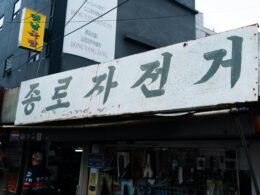 Ein Schild mit koreanischem Text hängt über dem Eingang eines Geschäfts und hebt die typische Beschilderung koreanischer Läden hervor.