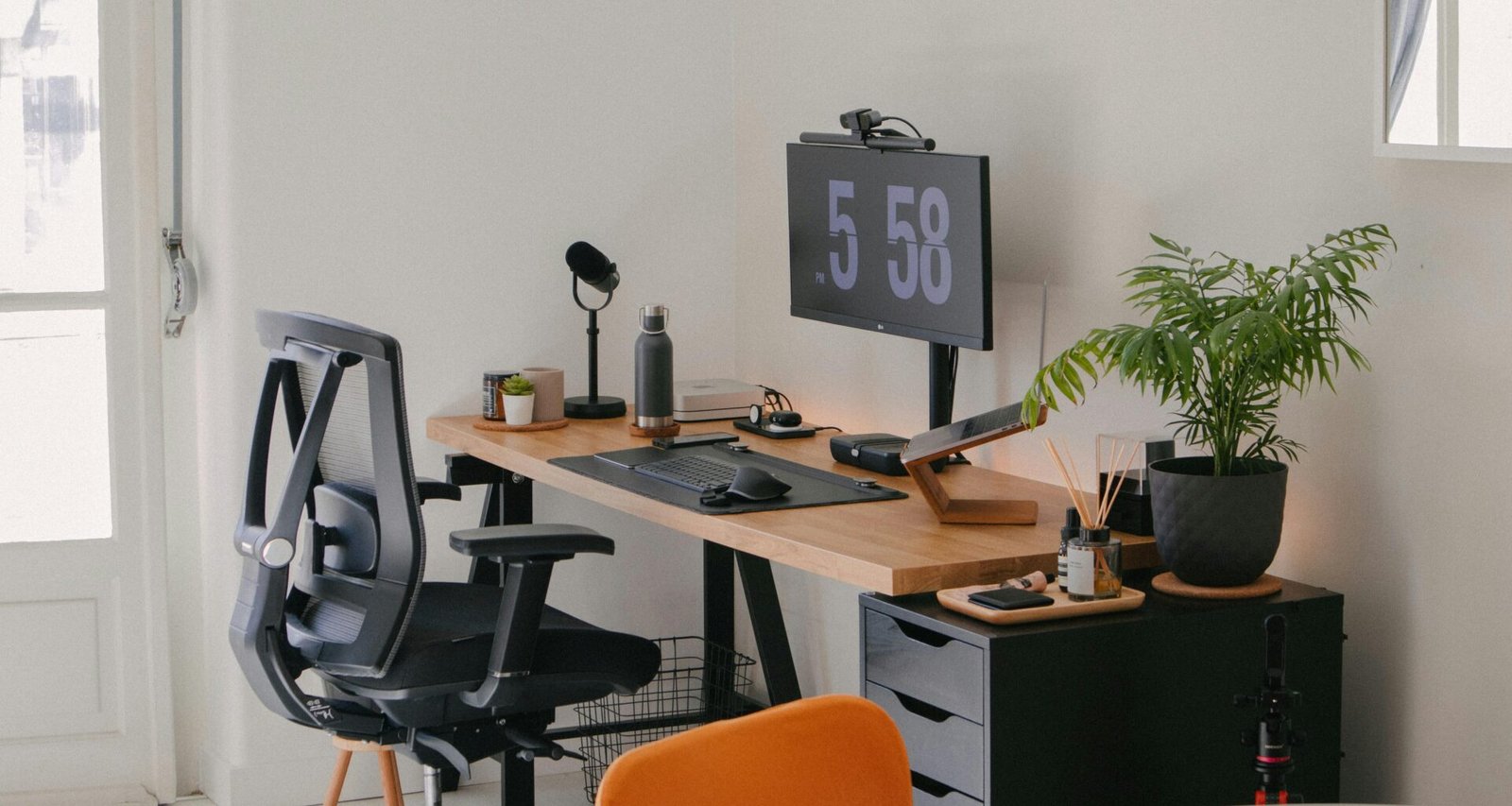 Ein Schreibtisch mit Computer und Stuhl steht in einem hellen, modern gestalteten Arbeitszimmer