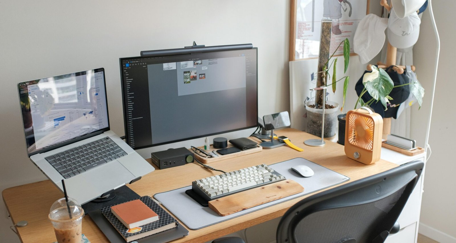 Ein Schreibtisch mit einem aufgeklappten Laptop und einem großen Computer-Monitor, ideal für produktives Arbeiten.