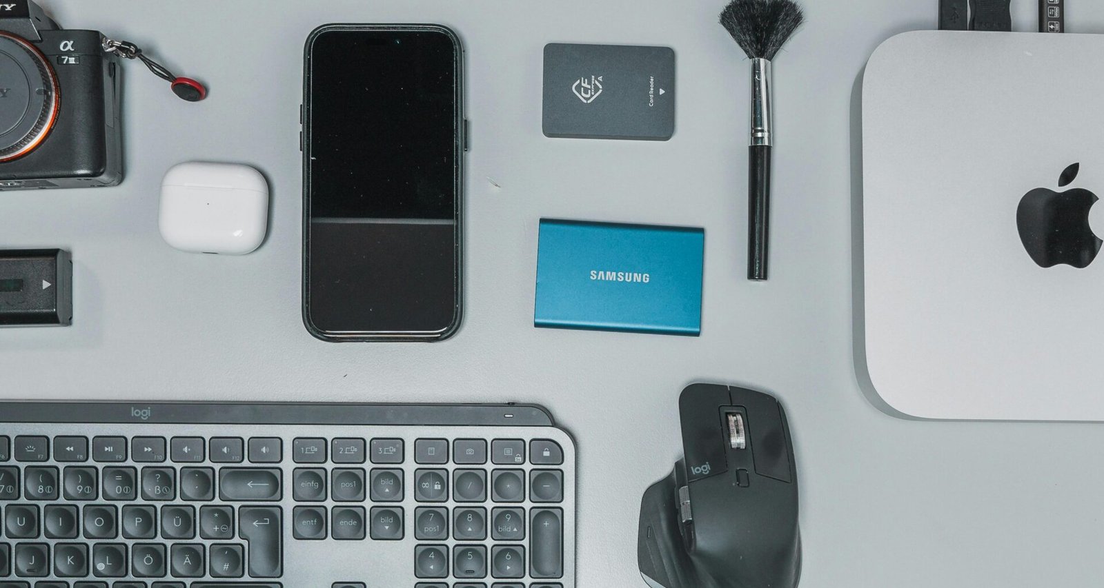 Schreibtisch mit Tastatur, Maus, Handy und weiteren Gegenständen für eine digitale Arbeitsumgebung