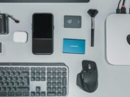 Schreibtisch mit Tastatur, Maus, Handy und weiteren Gegenständen für eine digitale Arbeitsumgebung