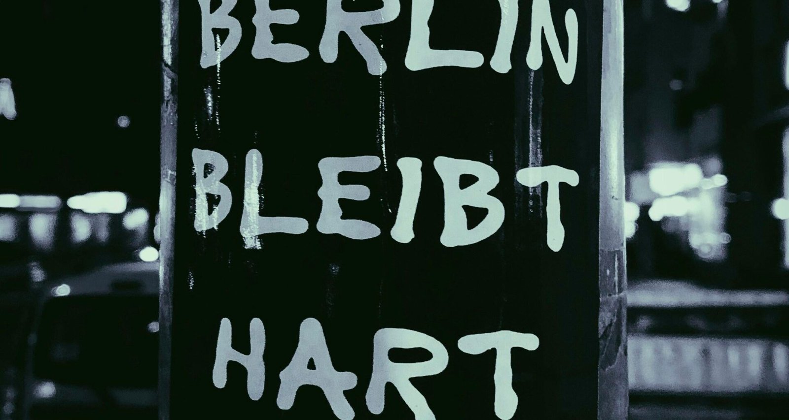 Schwarz-weißes Foto eines Schilds an einem Mast in einer städtischen Umgebung aus moderner Perspektive.