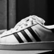 Schwarz-weißer adidas Superstar Turnschuh in Nahaufnahme vor neutralem Hintergrund