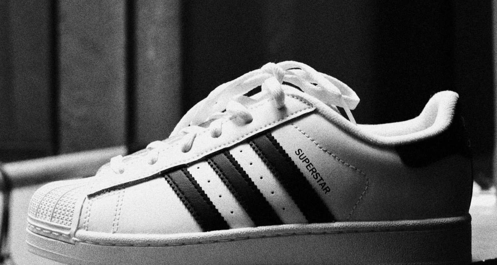 Schwarz-weißer adidas Superstar Turnschuh in Nahaufnahme vor neutralem Hintergrund
