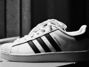 Schwarz-weißer adidas Superstar Turnschuh in Nahaufnahme vor neutralem Hintergrund