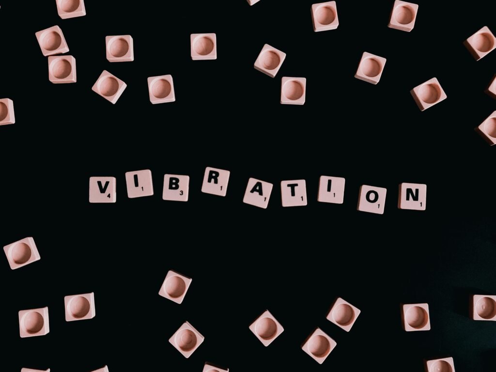 Schwarzer Hintergrund, darauf Würfel mit Buchstaben, die das Wort Vibration ergeben, abstrahiertes Technikmotiv