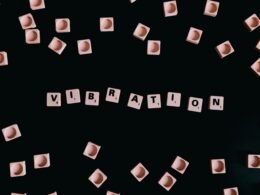 Schwarzer Hintergrund, darauf Würfel mit Buchstaben, die das Wort Vibration ergeben, abstrahiertes Technikmotiv