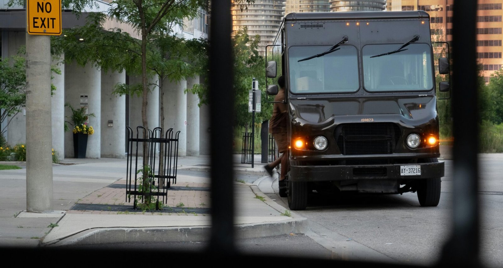 Schwarzer LKW fährt auf einer Straße entlang, flankiert von hohen Gebäuden im Hintergrund