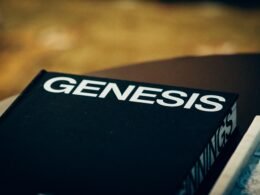 Schwarzes Buch mit dem Wort Genesis auf dem Umschlag, auf einer neutralen Oberfläche liegend, fotografiert von Jon Tyson