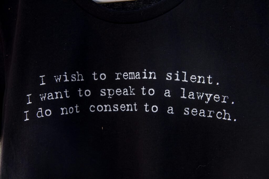 Schwarzes T-Shirt mit aufgedrucktem Gedicht liegt flach auf hellem Untergrund, aufgenommen von Dulcey Lima.