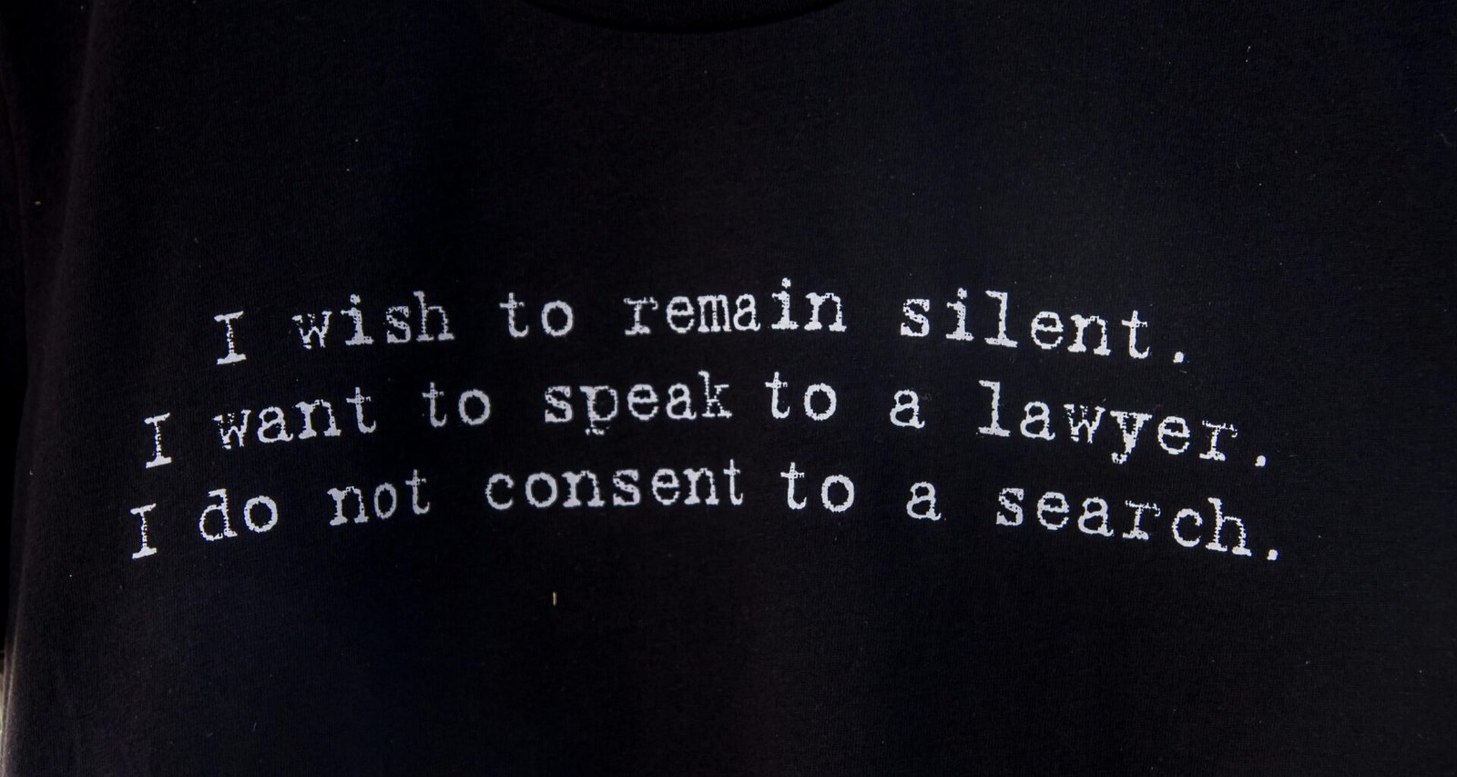 Schwarzes T-Shirt mit aufgedrucktem Gedicht liegt flach auf hellem Untergrund, aufgenommen von Dulcey Lima.