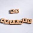 Nahaufnahme von Scrabble-Buchstaben, die die Worte 'My Journey' auf einem Spielbrett zusammensetzen.