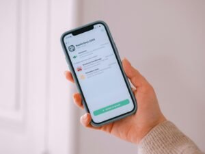 Hand hält ein Smartphone, auf dessen Bildschirm eine mobile Anwendung zu sehen ist, fotografiert von Swello