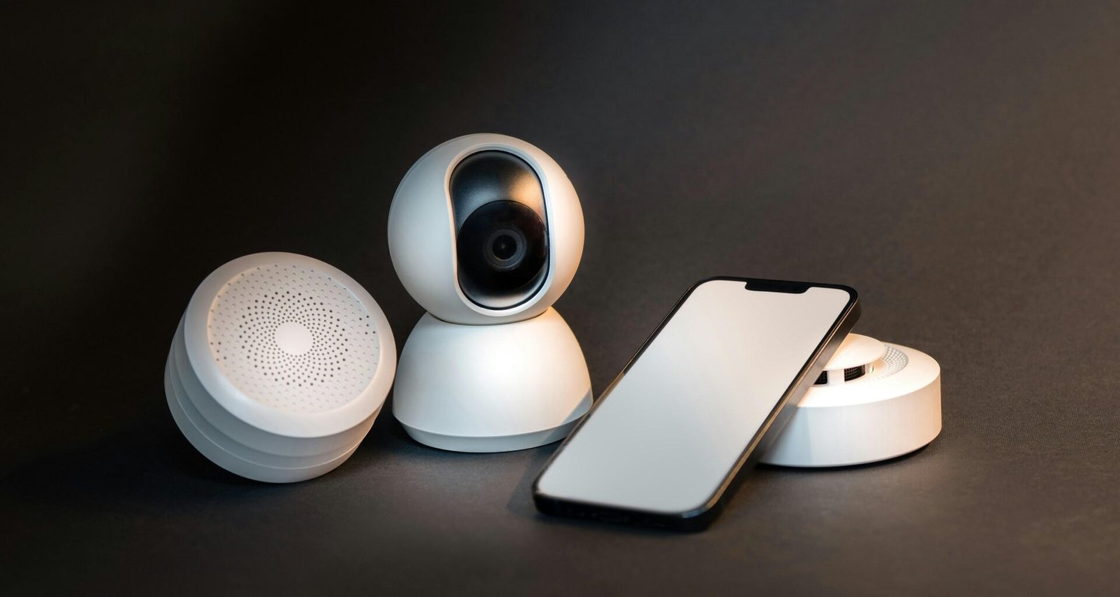 Ein modernes Smartphone liegt direkt neben einer kabellosen Überwachungskamera auf einem Tisch