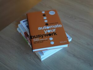 Ein ordentlicher Stapel Bücher liegt auf einem hellen Holztisch in ruhiger Atmosphäre, ideales Setting für Recherchen und Lernen.