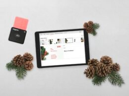 Ein Tablet-Computer steht auf einem Tisch neben mehreren Kiefernzapfen, Fokus auf Technik im modernen Umfeld.