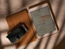 Tablet-Computer auf Tisch neben einer Geldbörse, Nahaufnahme, symbolisiert digitale und finanzielle Aspekte im Alltag.