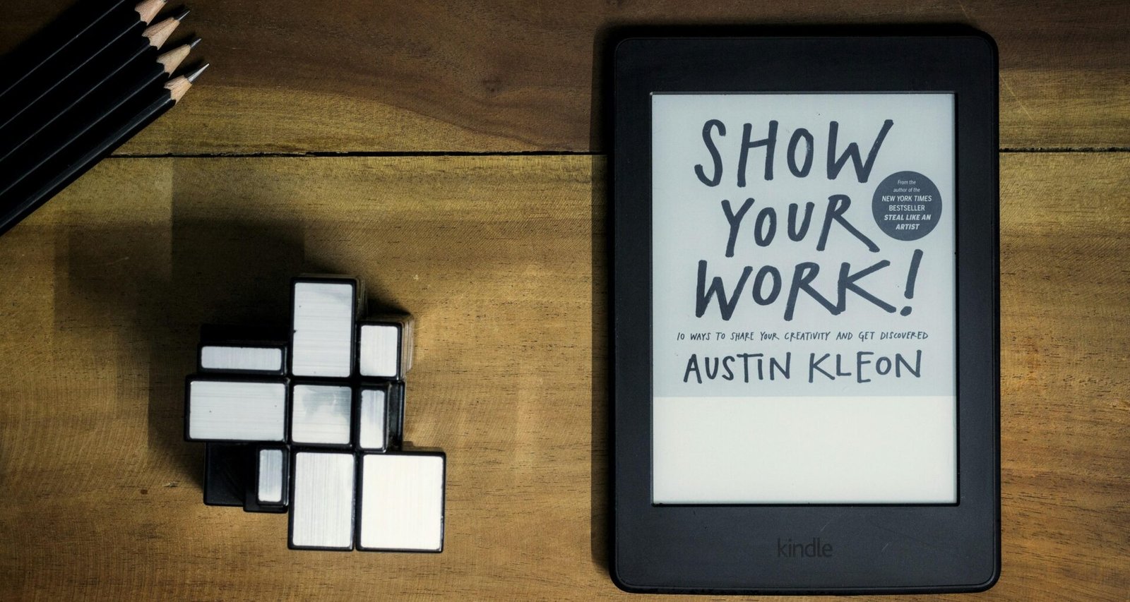 Ein Tablet mit einem aufliegenden Buch mit dem Titel 'Show Your Work', fotografiert auf einem hellen Untergrund.