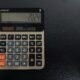 Ein moderner Taschenrechner liegt auf einer glatten Tischoberfläche und steht für genaues Arbeiten im Büro.