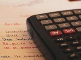 Ein Taschenrechner steht auf einem Blatt Papier und verdeutlicht Rechnen und Analyse im Büroalltag