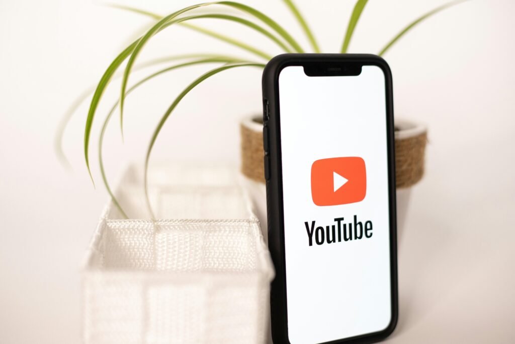 Smartphone mit YouTube-Logo neben einer kleinen Topfpflanze auf einem Tisch, ideal zur Darstellung von Video-Marketing-Themen