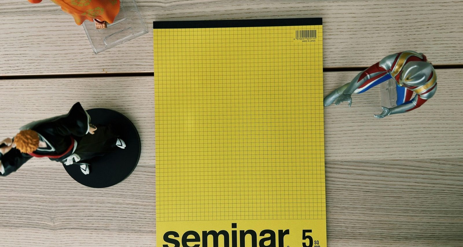 Ein gelbes Buch und eine silberne Schere liegen nebeneinander auf einem hellen Holztisch