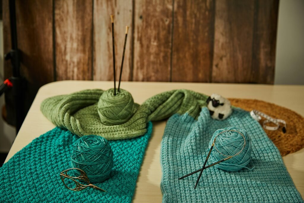 Blick auf einen Tisch, der mit bunten Wollknäueln und Stricknadeln für Handarbeitsprojekte ausgestattet ist