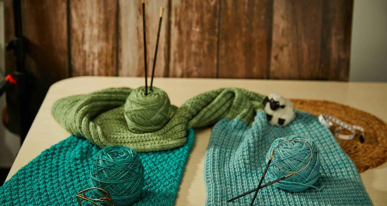 Blick auf einen Tisch, der mit bunten Wollknäueln und Stricknadeln für Handarbeitsprojekte ausgestattet ist