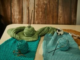 Blick auf einen Tisch, der mit bunten Wollknäueln und Stricknadeln für Handarbeitsprojekte ausgestattet ist