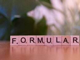 Auf einem Tisch legen Scrabble-Steine das Wort Formel, ideal für Artikel über Strategien oder Technologiekonzepte.