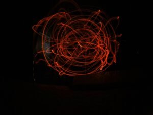 Verschwommenes rotes Objekt vor dunklem Hintergrund, modernes Beispiel für kreative Fotografie