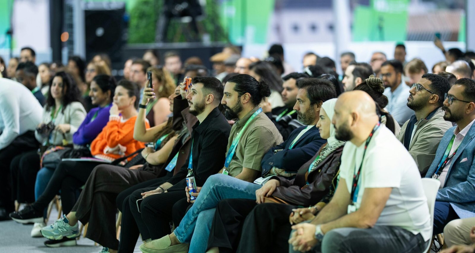 Eine gemischte Gruppe von Menschen hört aufmerksam einem Vortrag auf einer Konferenz zu, Fokus auf dem Publikum.