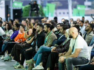 Eine gemischte Gruppe von Menschen hört aufmerksam einem Vortrag auf einer Konferenz zu, Fokus auf dem Publikum.