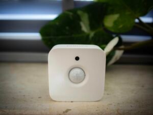 Weißer Sensor vor grünem Blattwerk, moderne Technologie in natürlicher Umgebung, Fokus auf Sensortechnik