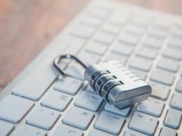 Ein Zahlenschloss liegt auf einer Computer-Tastatur und symbolisiert damit das Thema digitale Sicherheit und Datenschutz.