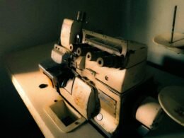 Eine antike Nähmaschine steht auf einem Holztisch und verdeutlicht historische Handarbeitstechniken.