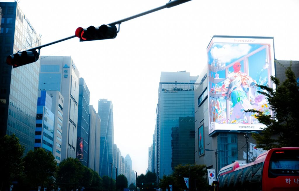 Eine Ampel hängt hoch über einer mehrspurigen Stadtstraße und steuert den fließenden Verkehr in einer urbanen Umgebung.