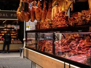 Im Laden hängen verschiedene Fleischstücke an Haken und werden zur Auswahl für Kunden präsentiert.