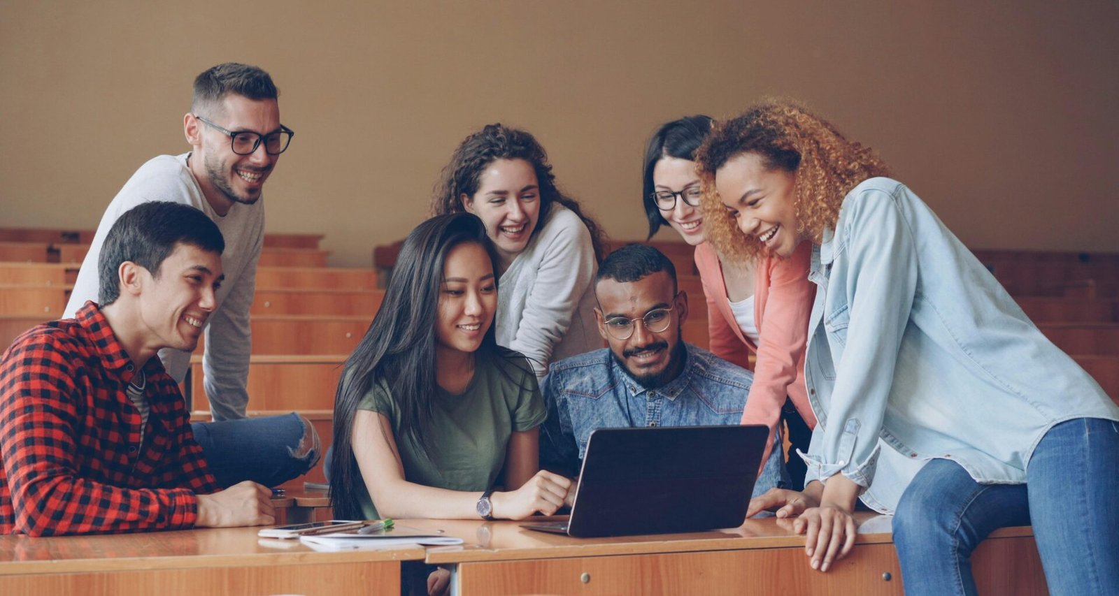 Mehrere Studierende mit unterschiedlichem Hintergrund diskutieren an einem Tisch zusammen vor einem Laptop
