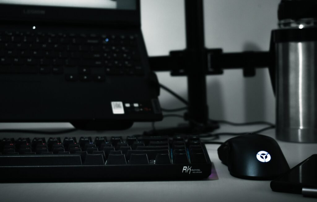Computer-Tastatur, Maus und Laptop auf einem Schreibtisch als moderner Arbeitsplatz für digitale Aufgaben