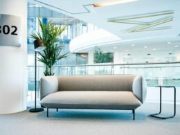 Ein modernes Wohnzimmer mit einem Couch und einem Tisch, platziert in einem schlichten, hellen Raum